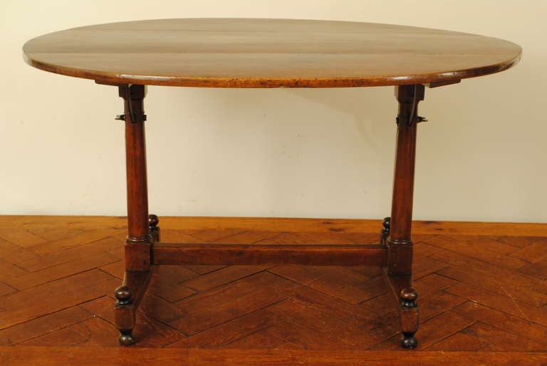 oval tilting top on double column supports on a trestle base raised on ball feet