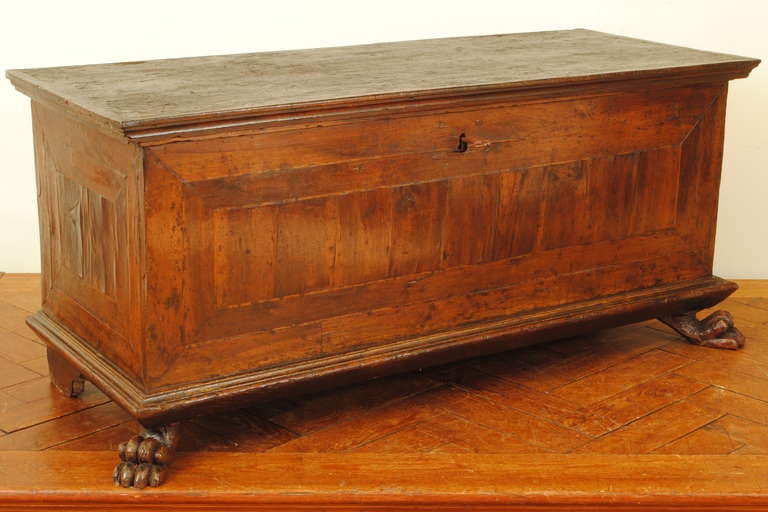 having a rectangular top with descending molded edge above a conforming case with front and sides veneered with conforming rectangular inlays of walnut and fruitwood, the molded bottom plinth-form base raised on rear bracket feet and front carved