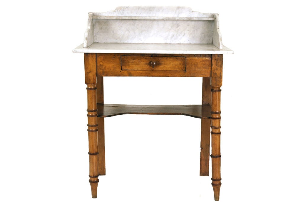 the marble top having an upper ledge, sides, and back above one drawer and a bottom shelf, the legs ring turned, the back legs flat