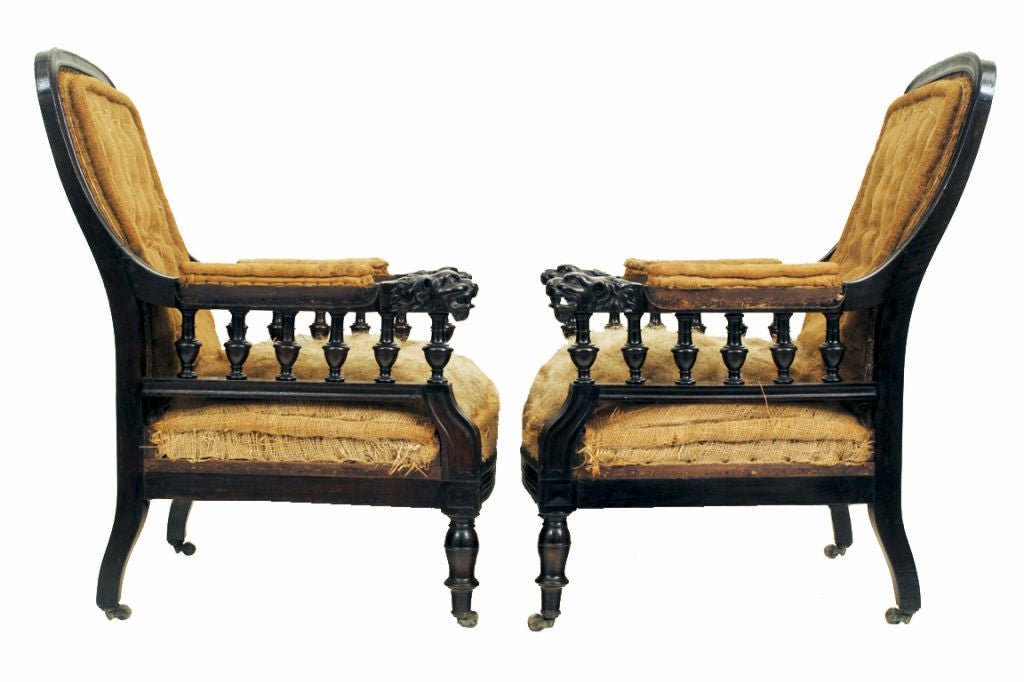 a pair of finely carved and turned library chairs, the curved and molded backrests continuing to animal carved arms supported by baluster turnings, with molded front rails, resting on vase ring and bulb turned feet, on original casters.  Our