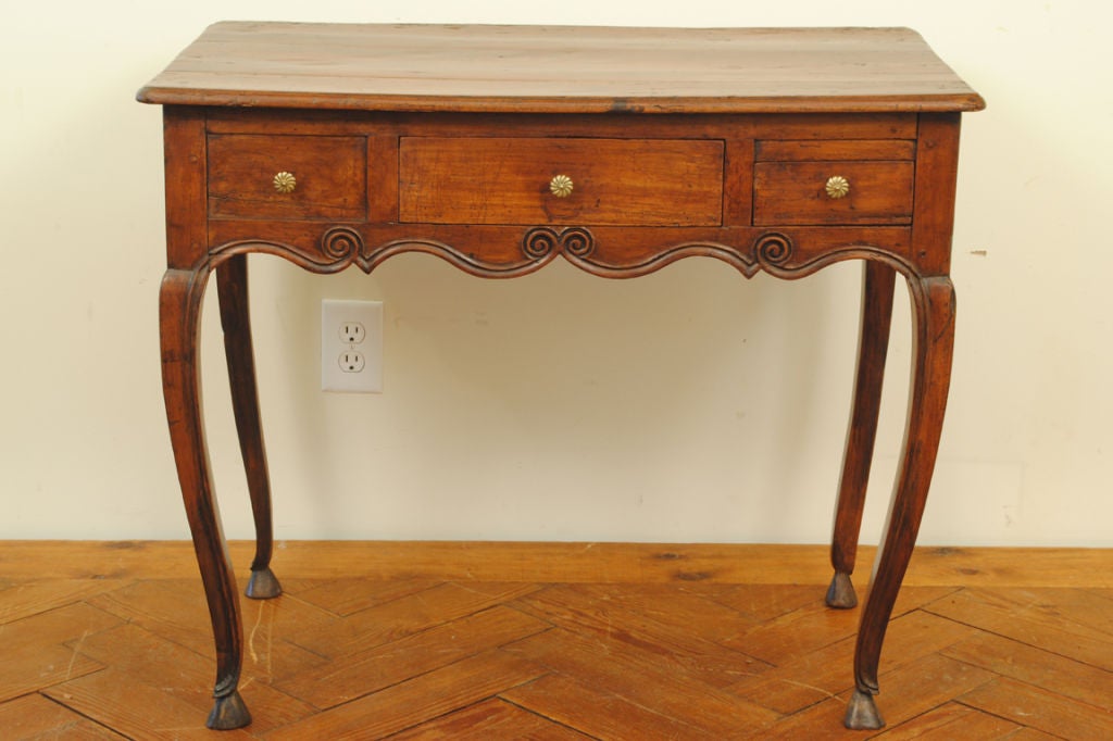 constructed entirely of cherrywood and of pegged construction, the five board top above a conforming case housing drawers and one faux drawer, having a carved and scrolling apron on three sides, the rear apron scrolling, the cabriole legs ending in