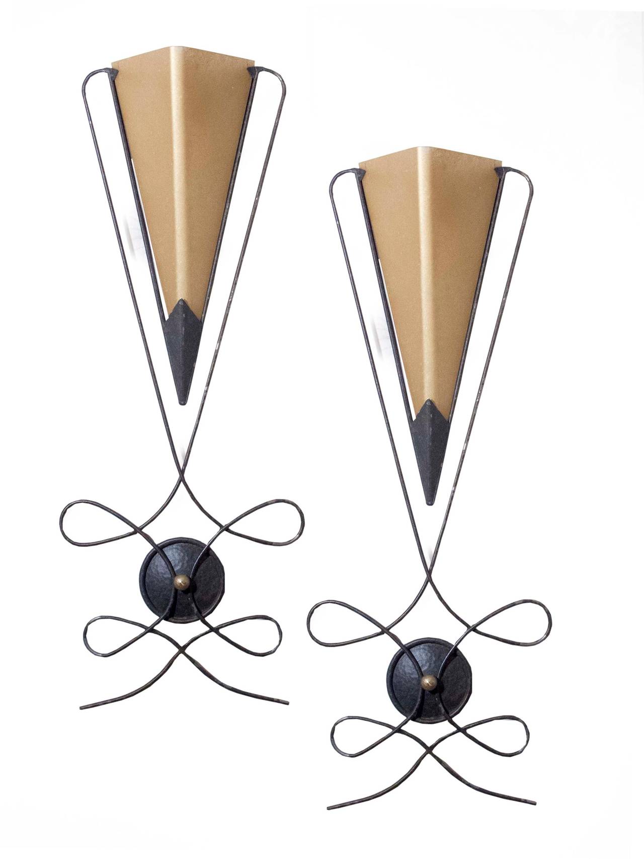 # ZA1077 - Decorative Mid-Century Modern pair of wall sconces. The triangular shaped translucent glass shades are framed by metal wire form trim above an interlocking playful design centering a roundel,
American, circa 1950.

Click on 