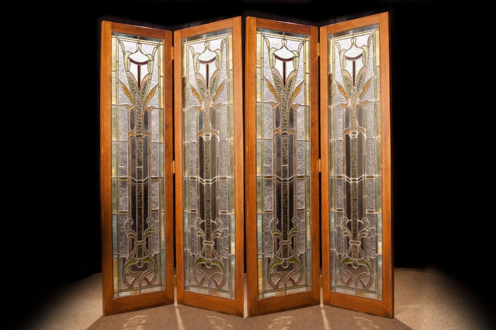 # S 227 - Decorative four panel mosaic glass screen mounted in an oak frame and hinged. The vertical mosaic glass panels of textured semitransparent and transparent glass form stylized scroll and leaf patterns with elongated geometric devices.