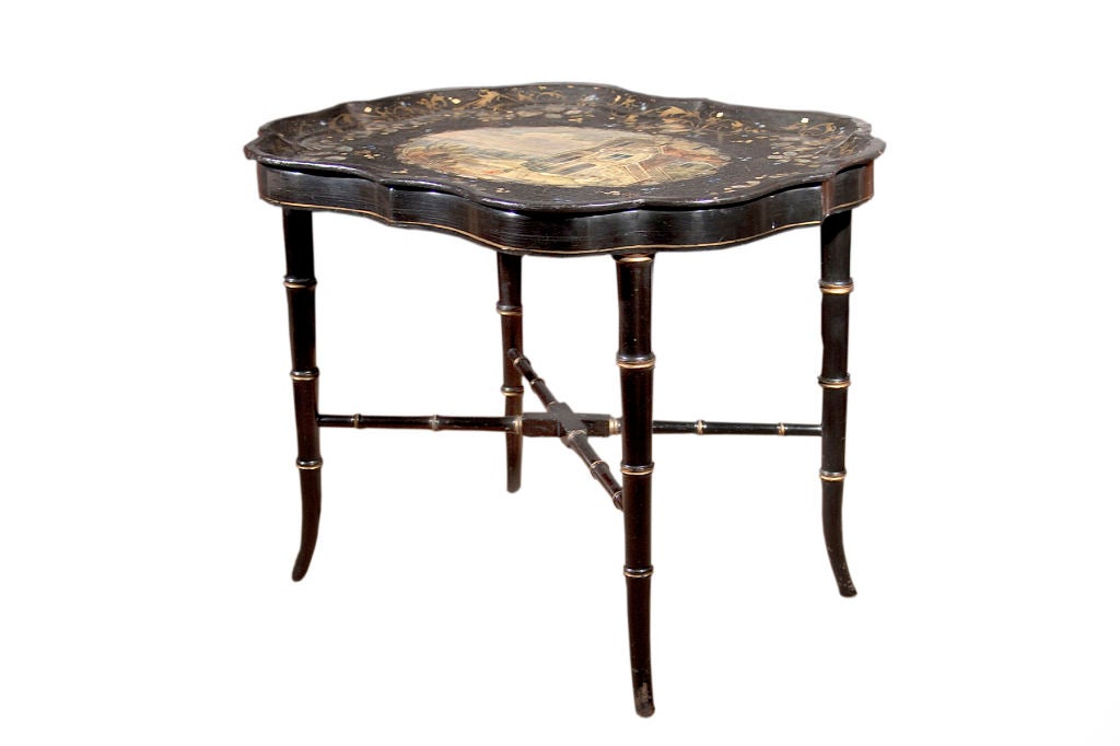 # T064- Victorian papier mache tray table on Stand. The shaped top centering a beautiful pastoral scene depicting a traditional English manor house surrounded by gilding and polychrome inlaid mother-of-pearl in foliate patterns, all resting on