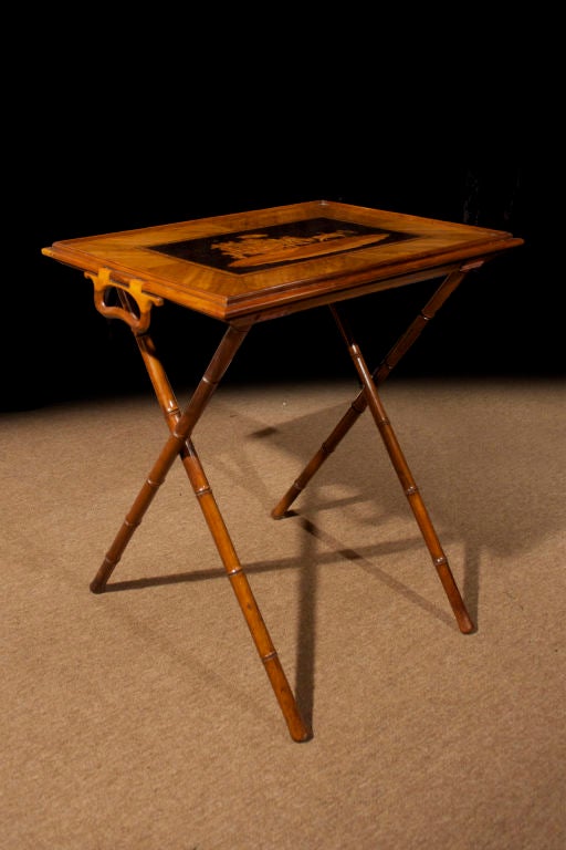 # T060 - Italian folding tray table with superb marquetry details. The rectangular tray with a pair of folding handles and banded borders surrounding a marquetry coaching scene. All raised on a simulated bamboo folding 