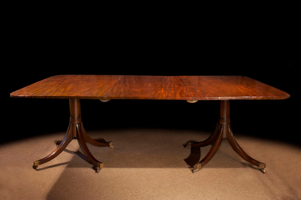 # W044 - Refined George III mahogany two pedestal dining table. The rectangular top with a rich mahogany grain and an additional leaf. All raised on turned pedestals ending in four splay legs ending in brass caps and casters.

See 