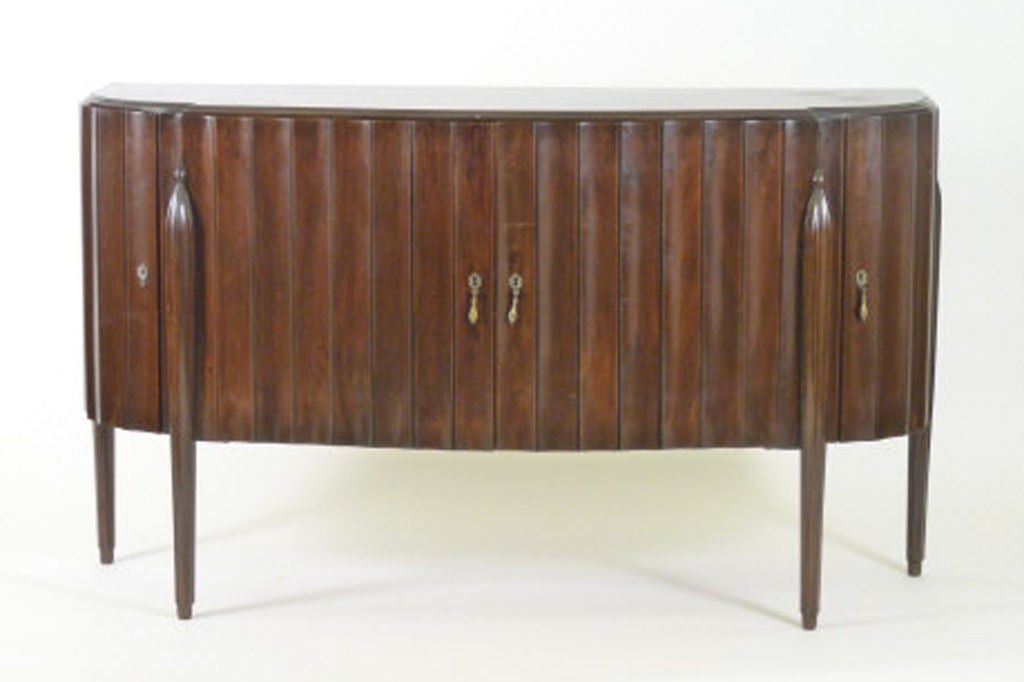 French Art Deco side cabinet after designs by Leleu. The molded bow fronted top above a wave fluted frieze with four doors. All raised on short round tapered legs decoratively treated at the top of each leg with a half spherical capital.<br