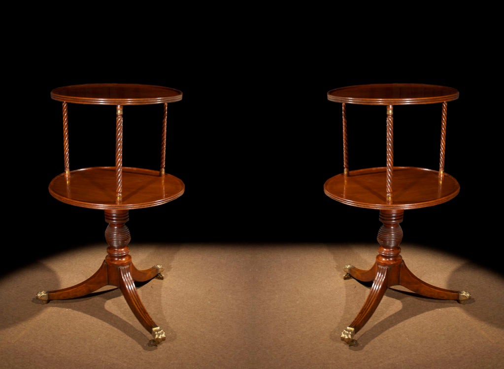 # V142 - Pair of Regency mahogany revolving dumbwaiters with circular top and reeded edge jointed by twist-reeded uprights to a larger tier rotating on ring-turned pedestal supported by three downswept reeded legs with brass paw feet and
