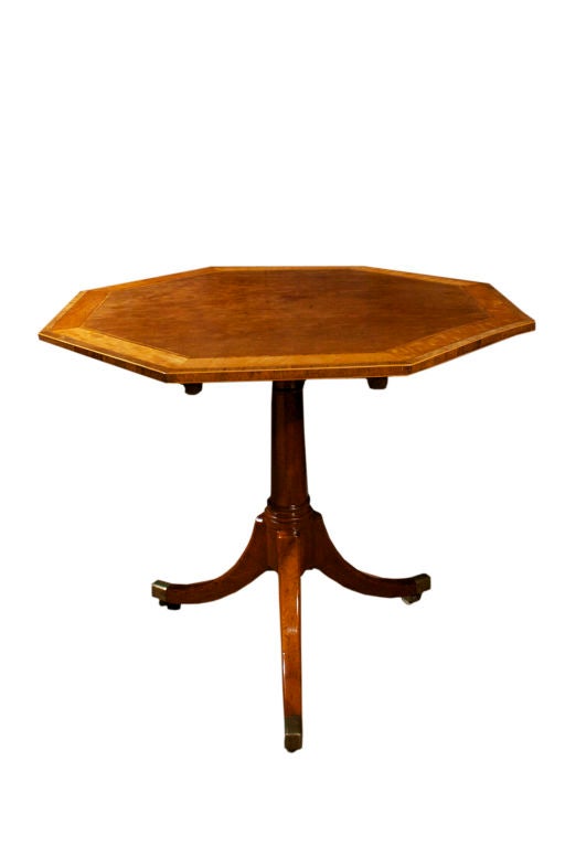 Refined Georgian octagonal table executed in mahogany with satinwood bandings. All in the manner of the Gillows, the well known London and Lancashire cabinet making firm.  The tilt top raised on a turned column support ending inelegant down swept