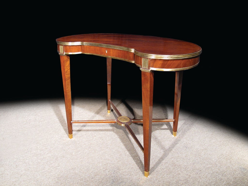 # W106 - Russian Neoclassical brass-mounted mahogany table in the Russian Jacob style having kidney shaped top with fluted brass edge above shallow frieze drawer, raised on square tapered legs surmounted by brass  fluting, joined by x-stretcher