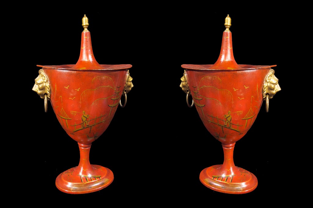 # W073 pair Anglo-Dutch tole covered urns decorated with gilt chinoiserie. The shaped tops with gilt finials. The elongated shaped urns on oval bases and gilt loop lion head handles. Decorated metal ware was sometimes referred to as 