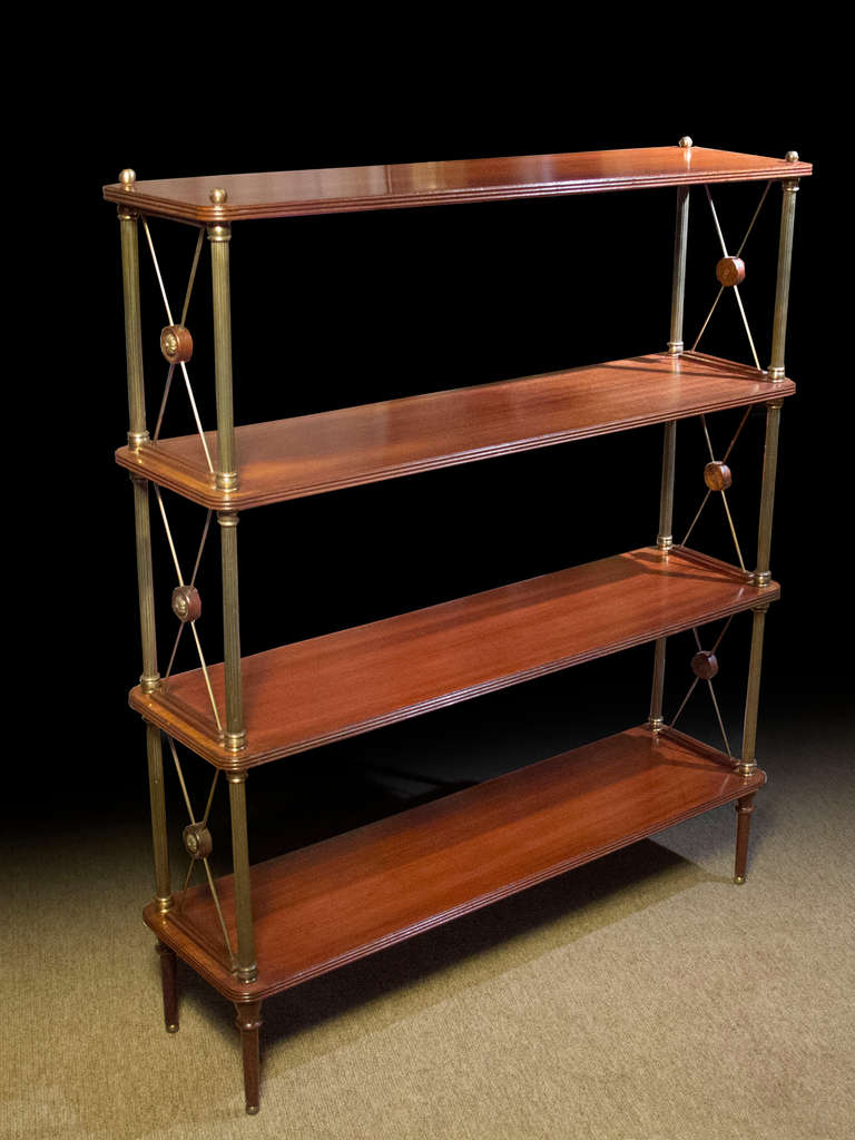 # A515 -  Mid-century etagere inspired by Regency designs. The four mahogany rectangular shelves supported on fluted brass columns connected by brass “X” cross supports centering mahogany and brass roundels.
For further discussion and similar