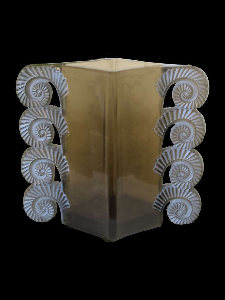 # A1025 - “Amiens” style Lalique vase. The cylindrical body flanked by four pairs of scrolled handles all in smoked glass with block signature R. Lalique and script number 1023.
French, early 20th century.

Click on 