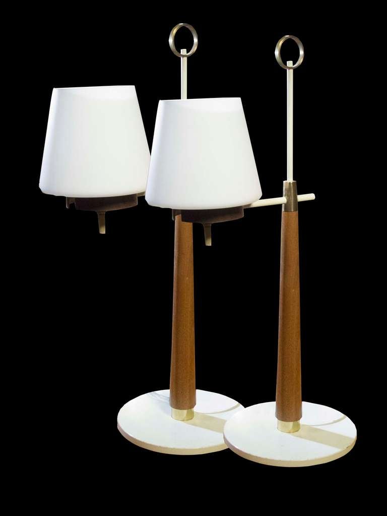 # A531 - Pair of Gerald Thurston designed table lamps manufactured by Lightolier. The turned walnut stems support a brass arm and shade surmounted by a brass ring finial and resting on a brass and white round base.
American, mid-20th