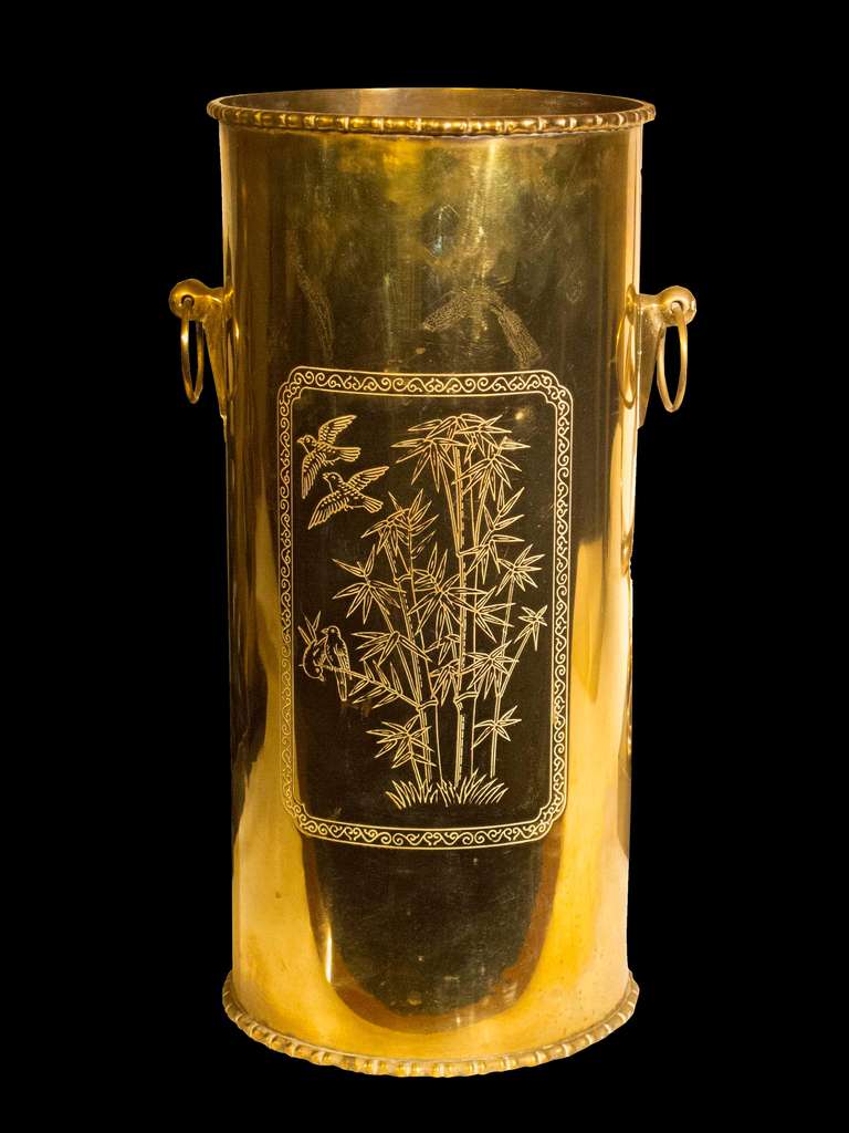 # A1048 - Mid Century brass umbrella stand in the Asian taste with a stylized bamboo rim. The front etched with cranes in an oriental landscape the reverse with small birds and two ring handles.<br />
Mid 20th Century<br />
<br />
*  Click on