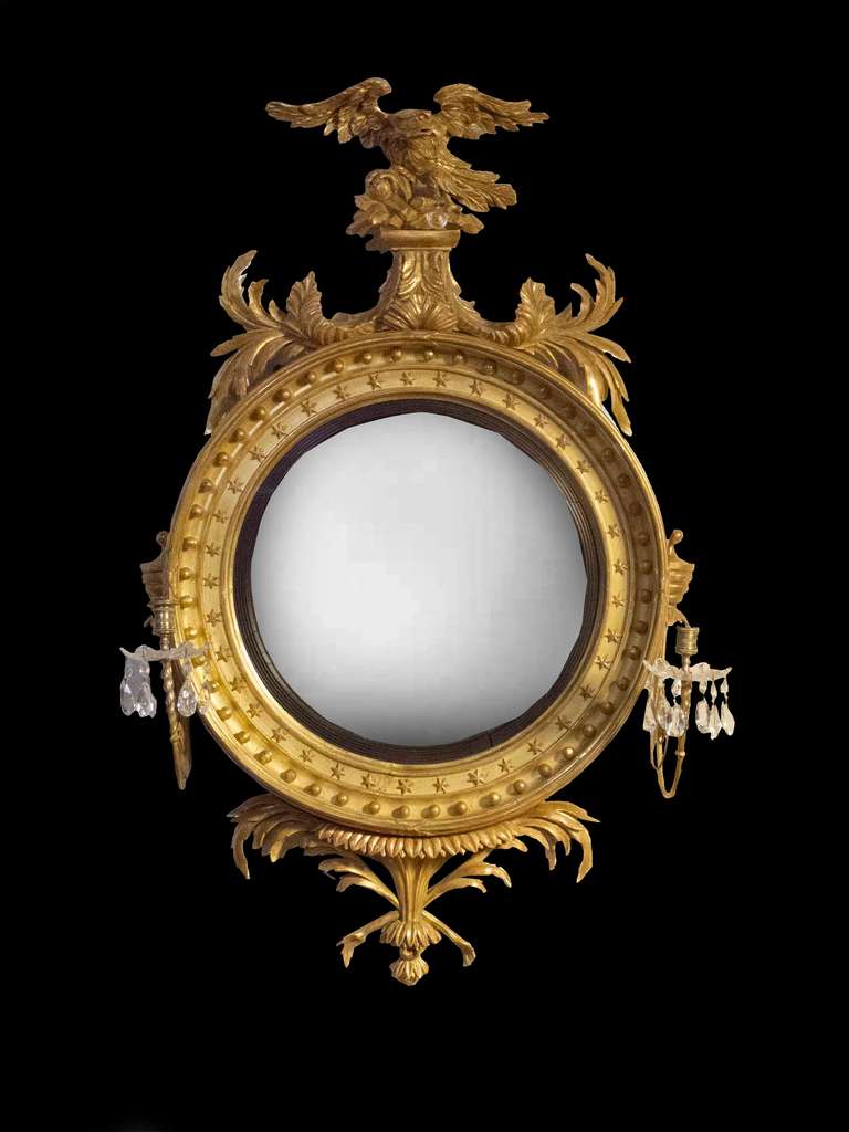 # A1054 - Elegant Regency giltwood convex mirror incorporating the neoclassical motifs of the period. The central round mirror plate surrounded by an ebonized filet molding followed by carved and gilded beading and a deep concave molding filled with