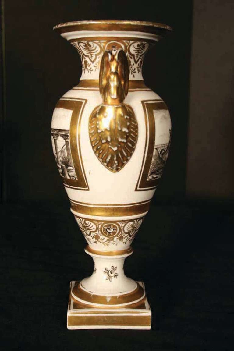 # S088 - Elegant pair of Paris porcelain urn form vases decorated with En Grisaille views of Classical Roman ruins, within gilt surrounds, flanked by gilt winged swan's head handles. Paris porcelain is a hard paste porcelain made in a number of