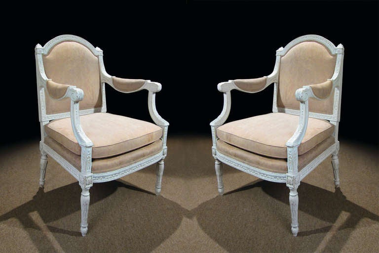# T506 - PAIR Louis XVI white painted and carved fauteuils in the neoclassical taste. The comfortable proportions enhanced with the upholstered back, pad arms, and  seat. The graceful arched crest rail flanked by finials, meet curved and molded arms