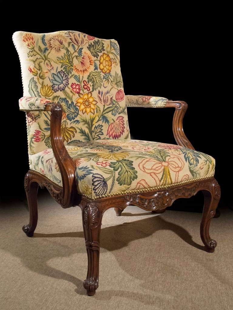 # A1019 - Mid-Georgian mahogany Gainsborough arm chair, after designs by Thomas Chippendale. Executed in mahogany, the Rococo inspired carving incorporates foliate details and 'C' and 'S' scrolls on the upswept arms, serpentine shaped apron, and