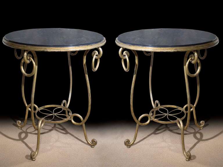 #ZA1069, rare pair of gilt and patinated wrought iron occasional tables in the Manner of René Prou (1889-1948.) The inset black slate tops surrounded by a metal apron all raised on four scrolled and twisted legs the top of which are hung with