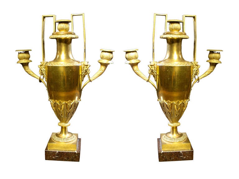 # Y044 - A rare PAIR Italian ormolu three-light candelabra in the Louis XVI manner. This elegant pair have urn shaped neoclassical bodies which are fire gilt and mounted with stylized classical leaves. The top of the urns are mounted with lions