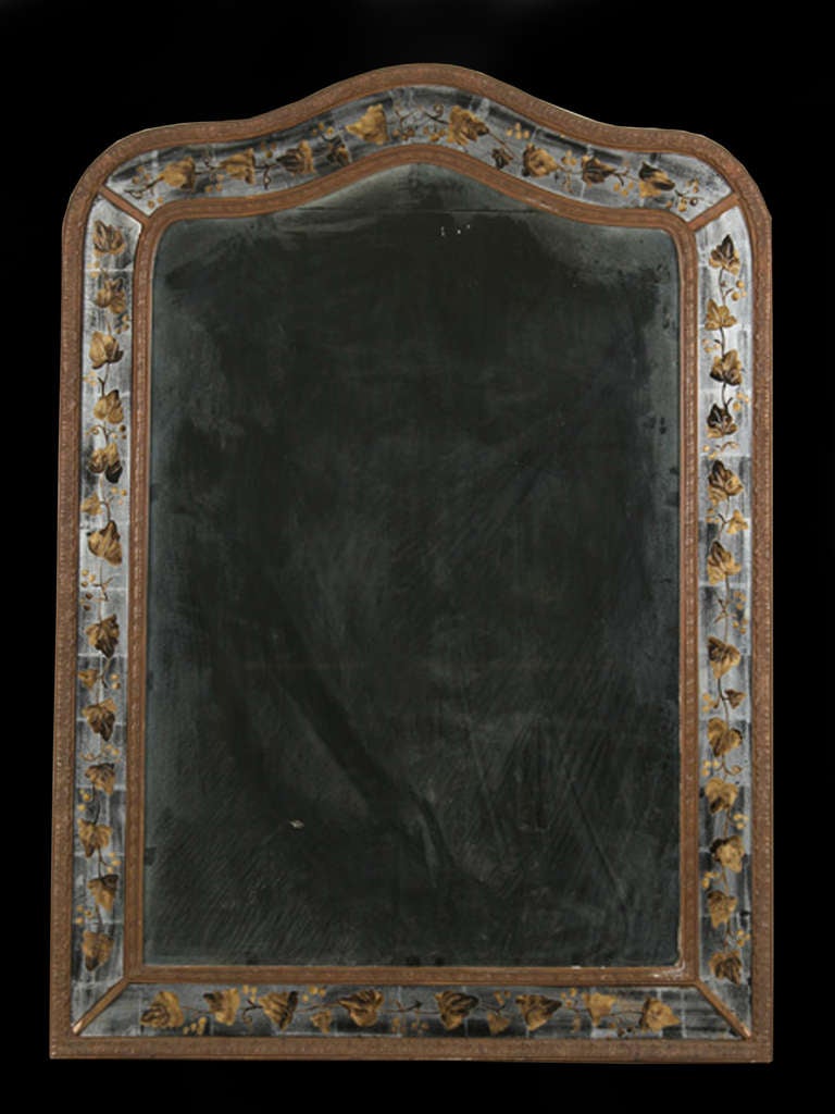 # Y085 - Verre Eglomise mirror by Jansen with a shaped top. The central rectangular mirror plate surrounded by a double carved giltwood border framing a finely painted Verre Eglomise border of leaves and scrolling foliage. 
 Maison Jansen was a
