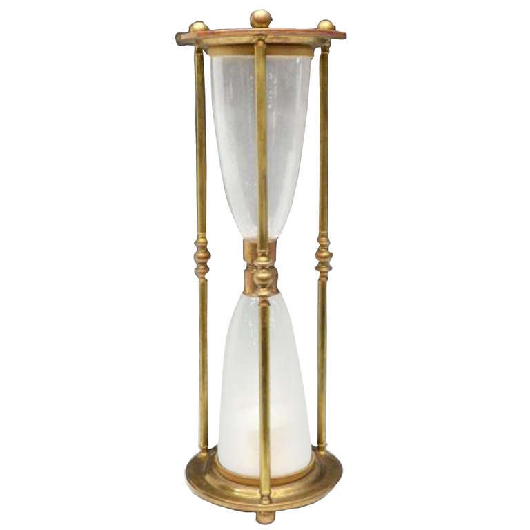 # Y087 - Large brass and glass hourglass sand timer having brass frame with glass containing white sand, supported on ball feet.

See similar examples of clocks, barometers, globes, grandfather clocks, grandmother clocks and case clocks on our