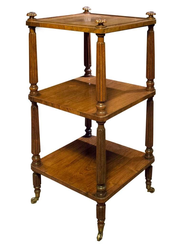 # Y058 - Regency rosewood three-tier etagere whatnot, having rosette finials above an edged top. The three shelves are raised on reeded supports which rest on toupie feet and brass castors.
English Circa 1815

See similar examples of etageres on