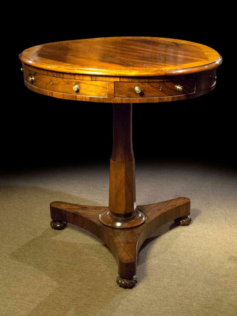 # Y095 - Regency small drum table executed in nicely figure rosewood. The round top veneered with a cut corner border above a narrow frieze with drawers. All raised on a pedestal support resting on a tripartite plinth base ending in bun feet.

