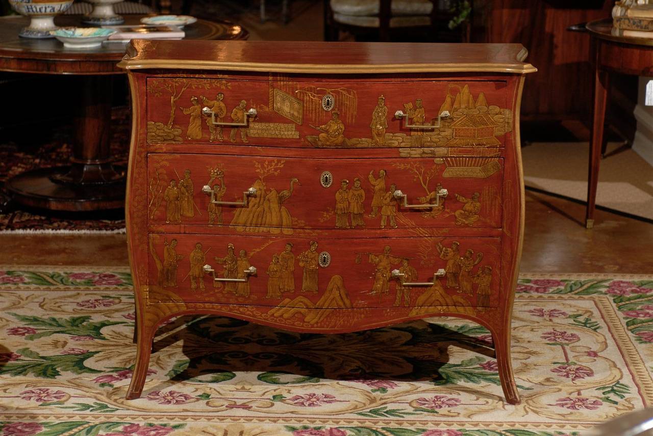 A lovely Mid-Century three-drawer bow front chest. The color has a nice coral/red tone with gold oriental paintings.