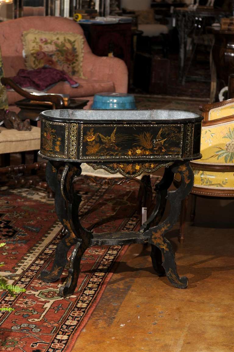 This is a beautiful late 19th century chinoiserie-decorated jardinière. It has an oval body with mother of pearl inlay, shaped legs and feet joined by platform stretcher. It has the original metal liner

#314-194