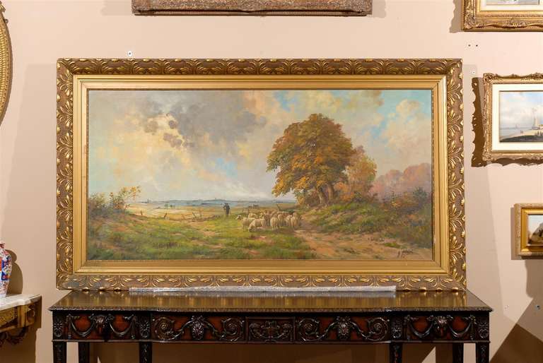 Large oil on canvas landscape of sheep and shepherd in the meadow with a body of water and city faintly seen on the horizon.  Original carved wood frame.  Very well done.  Makes a statement on any wall of your home or office.