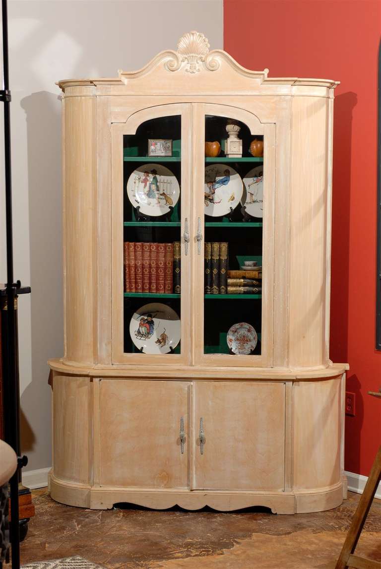 White washed midcentury China cabinet with a charming, carved shell top. Two top glass doors house four shelves, painted green with, two lower wooden doors which contain two additional shelves. The antique styled oval pulls add a distinctive touch