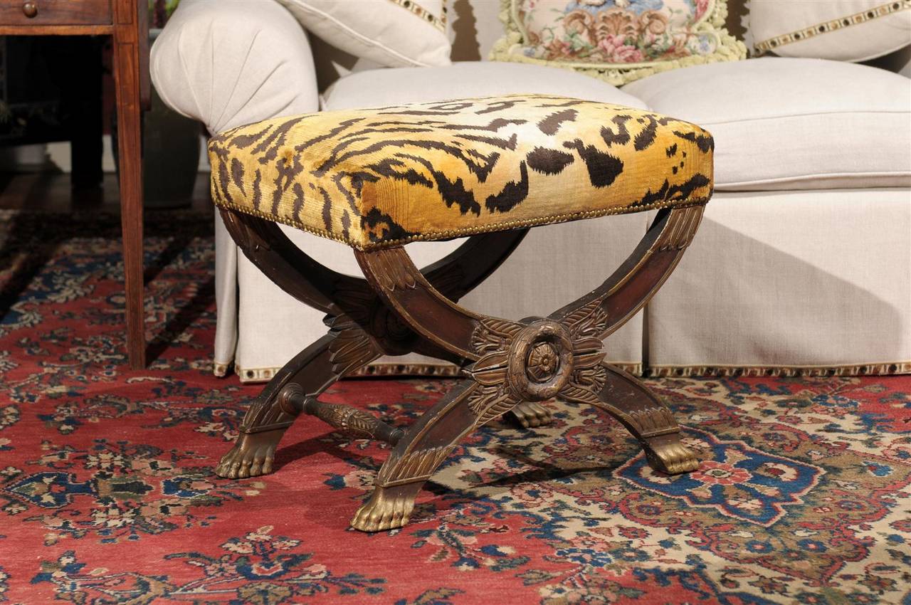 This is a wonderful bench with carving, center medallions on both sides and paw feet. It is upholstered in a velvet animal print.