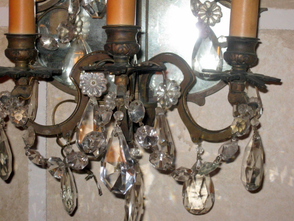 Beautiful pair of crystal and bronze sconces with a mirrored back
