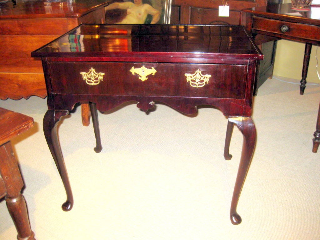 Queen Anne mahogany tea table with cabriole legs and pad feet. It has an unusual apron and the original escutcheons.