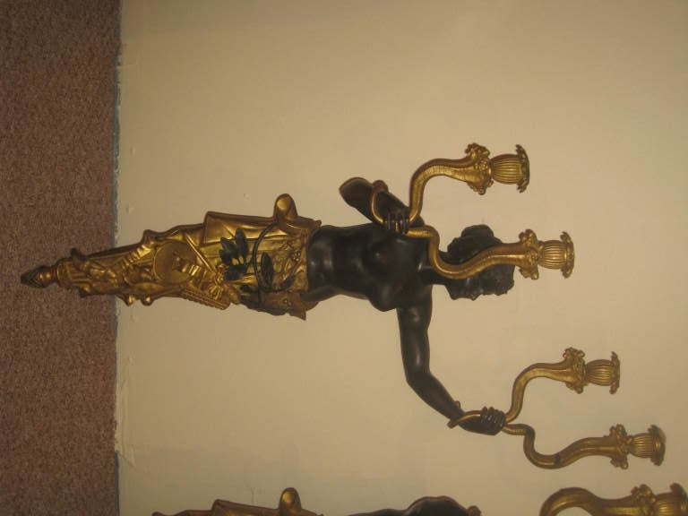 A large dramatic pair of figural patinated bronze and gilded sconces.
