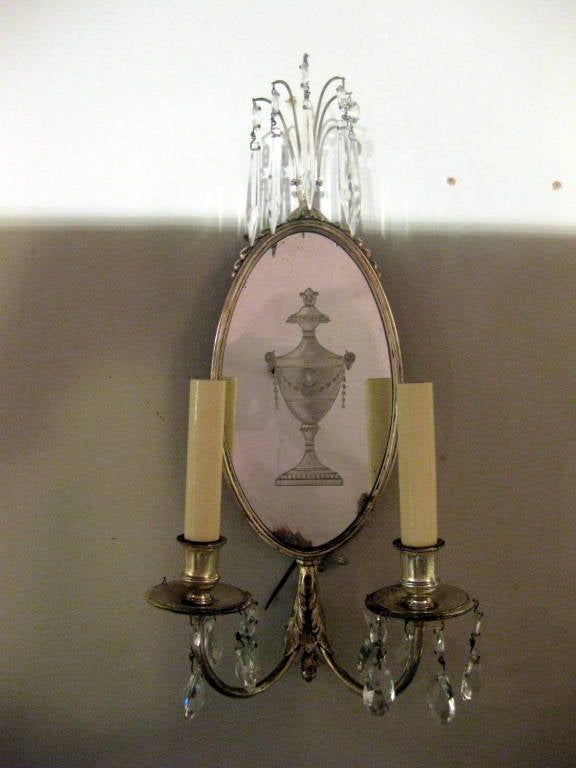 Two pair of silverplated sconces with a neoclassical urn etched in the mirrored backplates, and with hanging crystals. (can be sold per pair)