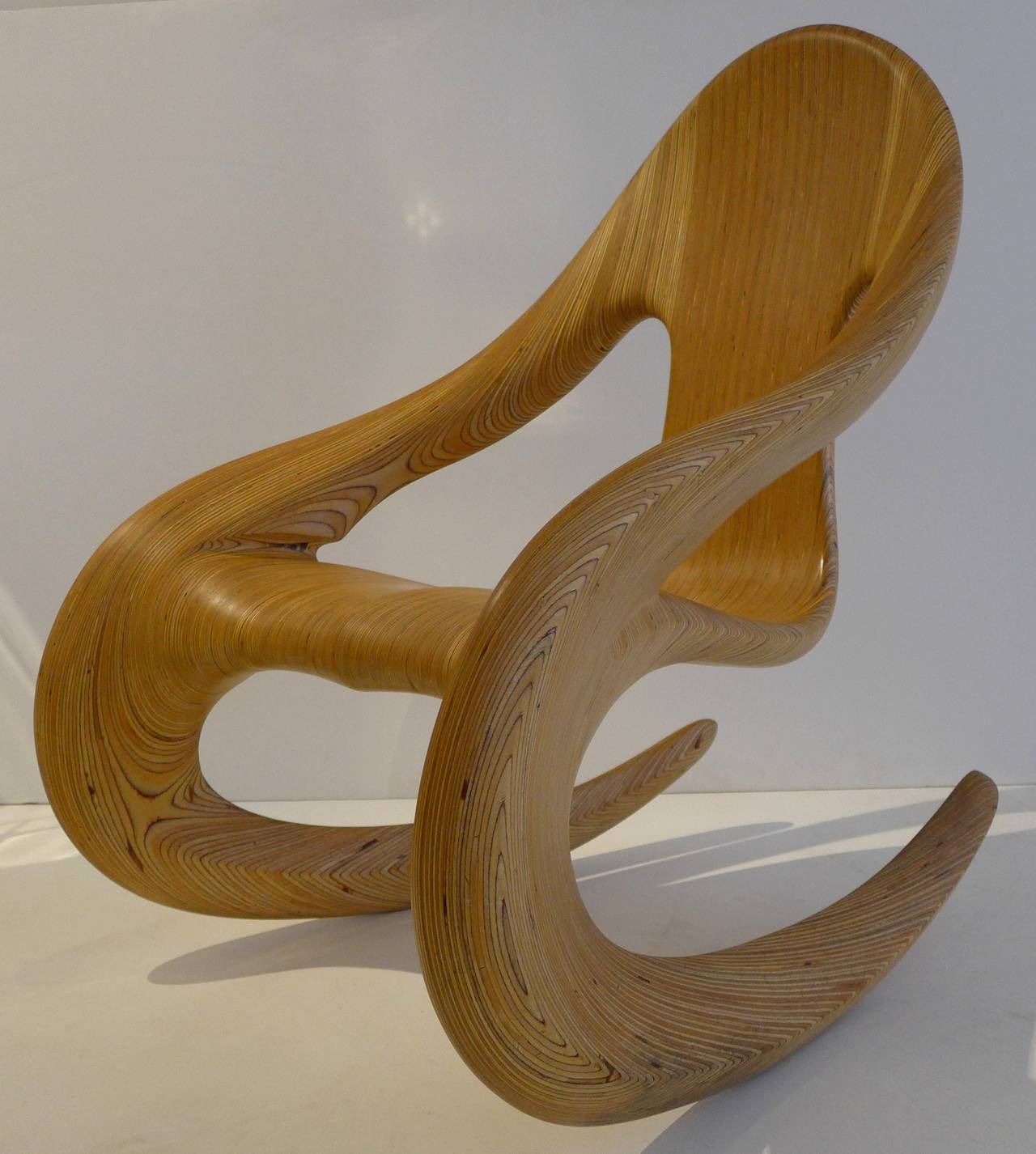 Dramatically sinuous, yet comfortable, rocker by Wisconsin woodworker Carl Gromoll (b. 1950), executed in 1987. Meticulously and intensively handcrafted of stack-laminated, carved, and polished Baltic birch. Gromoll began making wooden objects in