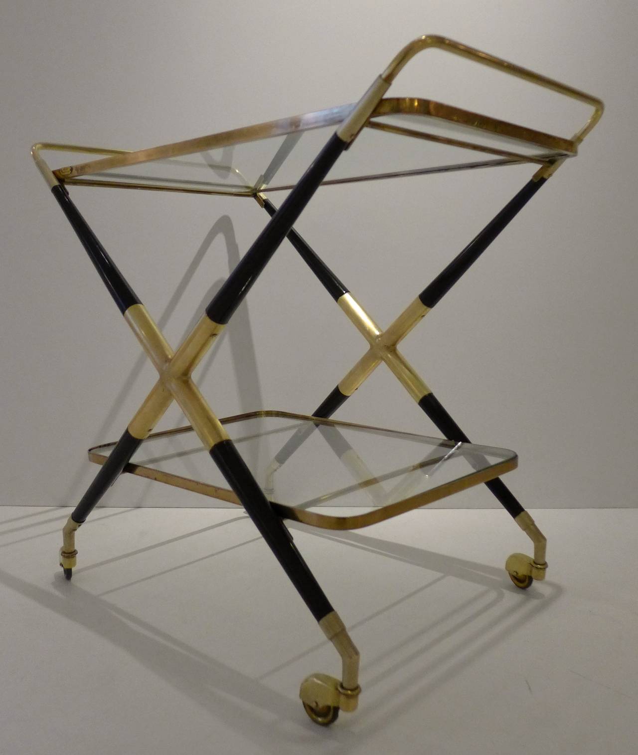 Bar cart or trolley in brass, walnut, and glass with metal casters.  Made in Italy, c. 1950's.  This design is usually assigned to Cesare Lacca.  With a metal 