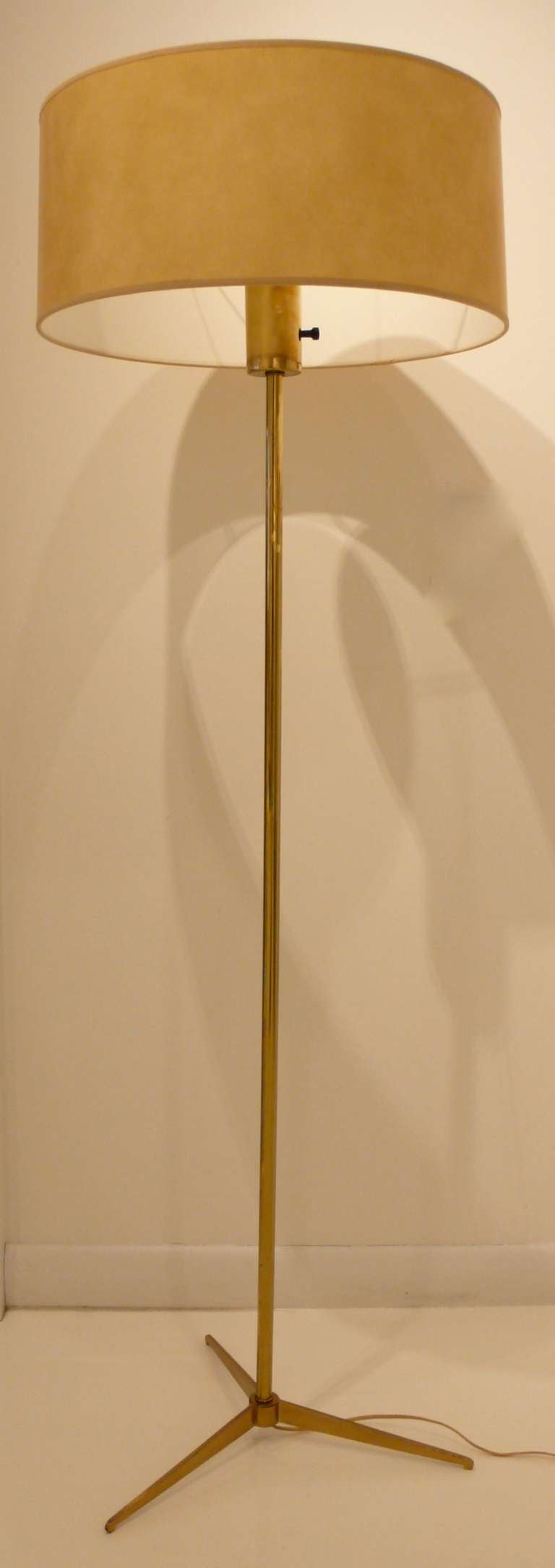 Floor lamp of brass-plated metal with a tripod base by Ernest Lowy for Koch and Lowy, c. 1950's.  Custom parchment shade made on original wire frame.  Areas of wear to the brass plating; otherwise excellent condition.  Ref: Hennessey, 