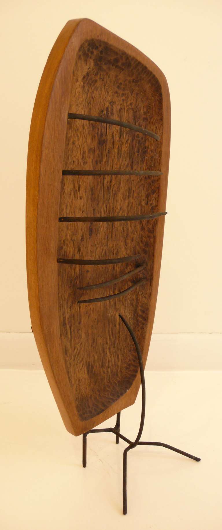 Eccentric and interesting abstract sculpture of carved and hewn wood with curved iron spikes on one side and strips of wood on the other; atop a nicely integrated wrought iron base.  By Washington, DC,  artist Jennie Lea Knight (1934-2007).  Knight