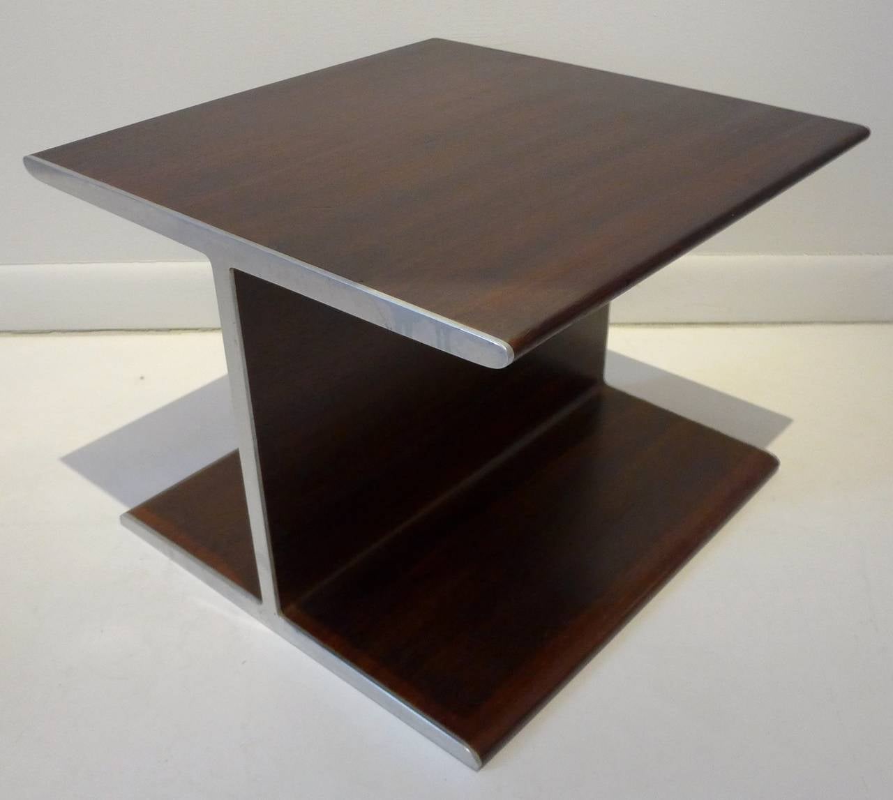 I-shaped table in walnut with steel edging on opposing sides.  An unusual mid century design that can serve as a side table or pedestal. Reminiscent of the steel i-beam tables Ward Bennett designed for Brickel, with the obvious substitution of wood