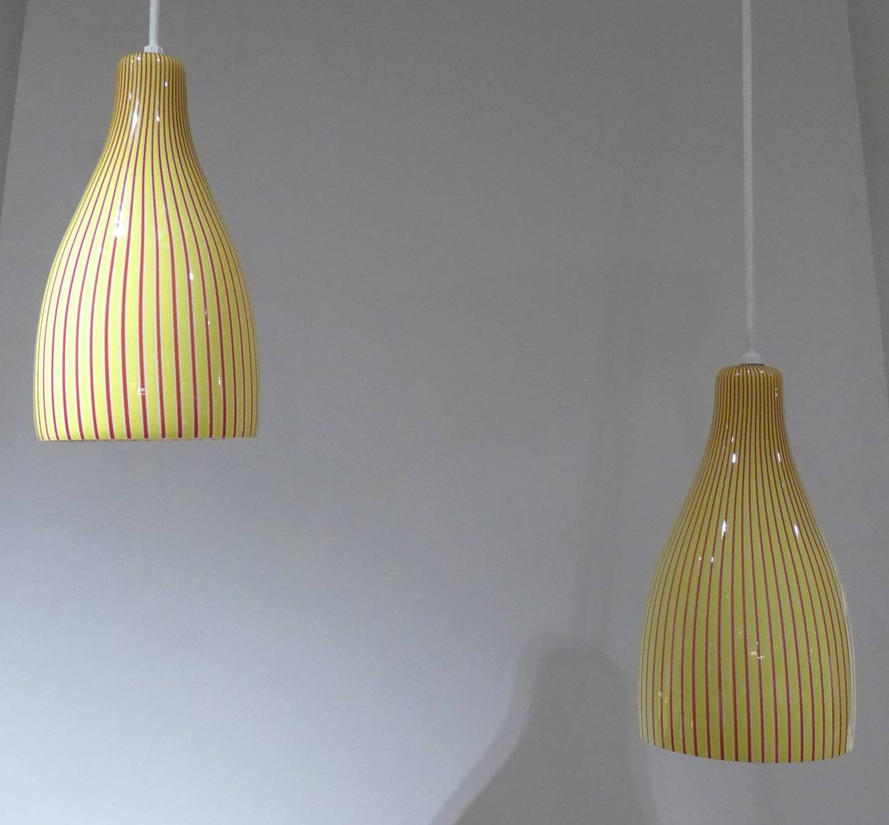 Two pendant lamps with yellow and purple stripes in cased white matrix. Handblown by Venini, circa 1958. Purchased directly from the Venini factory by the previous owner. Rewired. Glass in mint original condition. Priced individually.