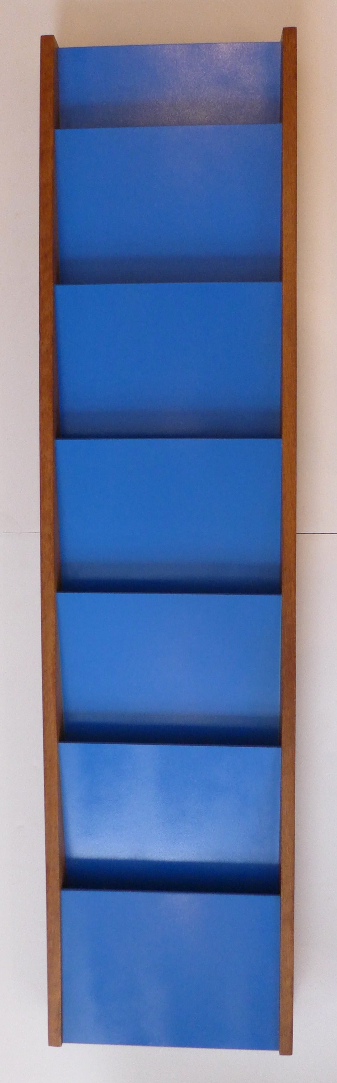 Wall-hanging magazine rack of lacquered masonite and walnut, made by Peter Pepper Products of California, c. 1960's.  A colorful way to organize papers or publications.  The walnut sides are in good original condition; the masonite panels have been