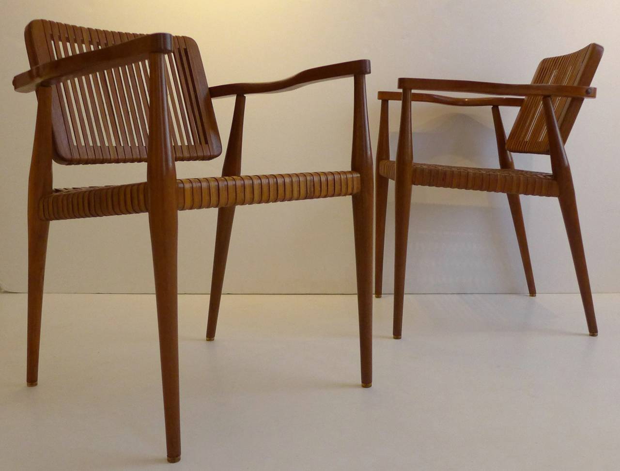 Unusual and striking set of four armchairs in walnut with sinuous arms, pivoting back rests, and woven rattan seats. Designed by Marcel La Riviere and made by his company, La Riviere, Inc, for Ficks Reed. Likely only produced for a few years in the