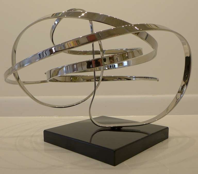 Kinetic sculpture composed of three undulating ribbons of stainless steel poised on a pivot point, all sitting atop a polished marble base. By electronic technician-cum-sculptor Michael Cutler (b. 1947), a self-taught California artist who began