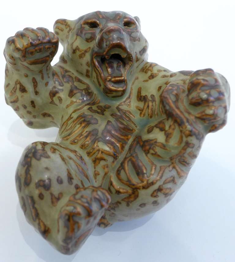 Ceramic sculpture of a bear in a playful posture, with a Saltoesque green and brown glaze, by Danish designer Knud Kyhn, executed by the Royal Copenhagen faiance works (Aluminia), c. 1960's.  Fully marked, in excellent condition.