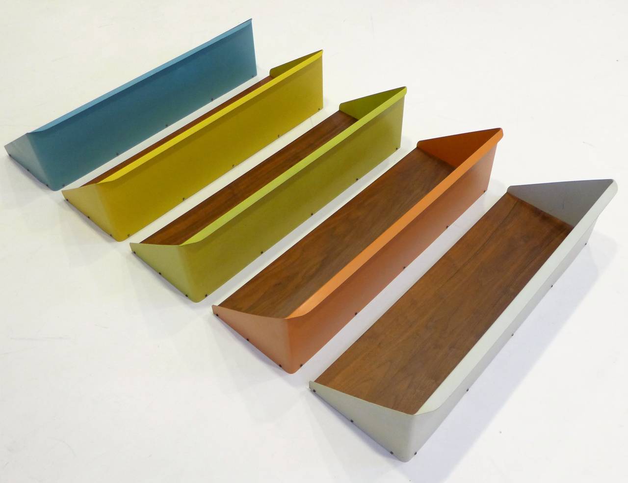 Five hanging shelves of bent and lacquered sheet metal and walnut, in a graduated range of colors, with a very Mad Men look.  Most likely from Denmark, 1960's, though the colors also have a California 1960's vibe. Maybe Cado meets Peter Pepper