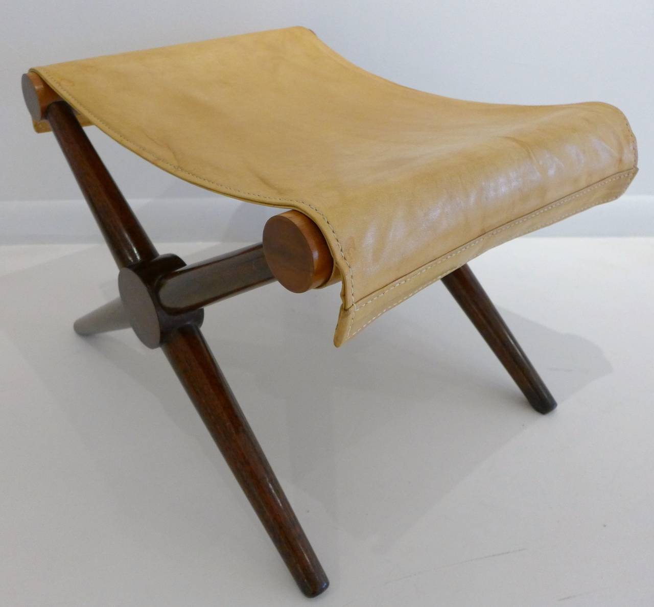 X-base campaign bench of walnut and birch with a leather sling. After a model by Paul Rodocanachi for Jean Michel Frank. From the Champ Soleil in Newport, RI, and the estate of Russell Barnet Aitken. Aitken (1910-2002) was a noted ceramic artist,